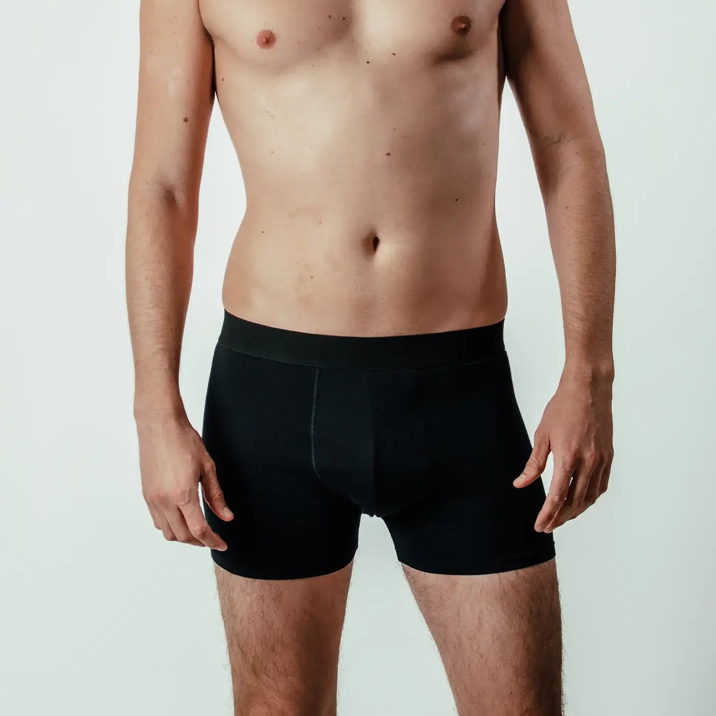 Front view of man wearing black bamboo boxer briefs against plain background