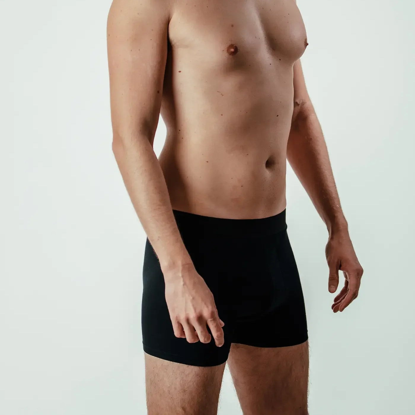 male model wearing black bamboo boxer briefs, side view, plain background