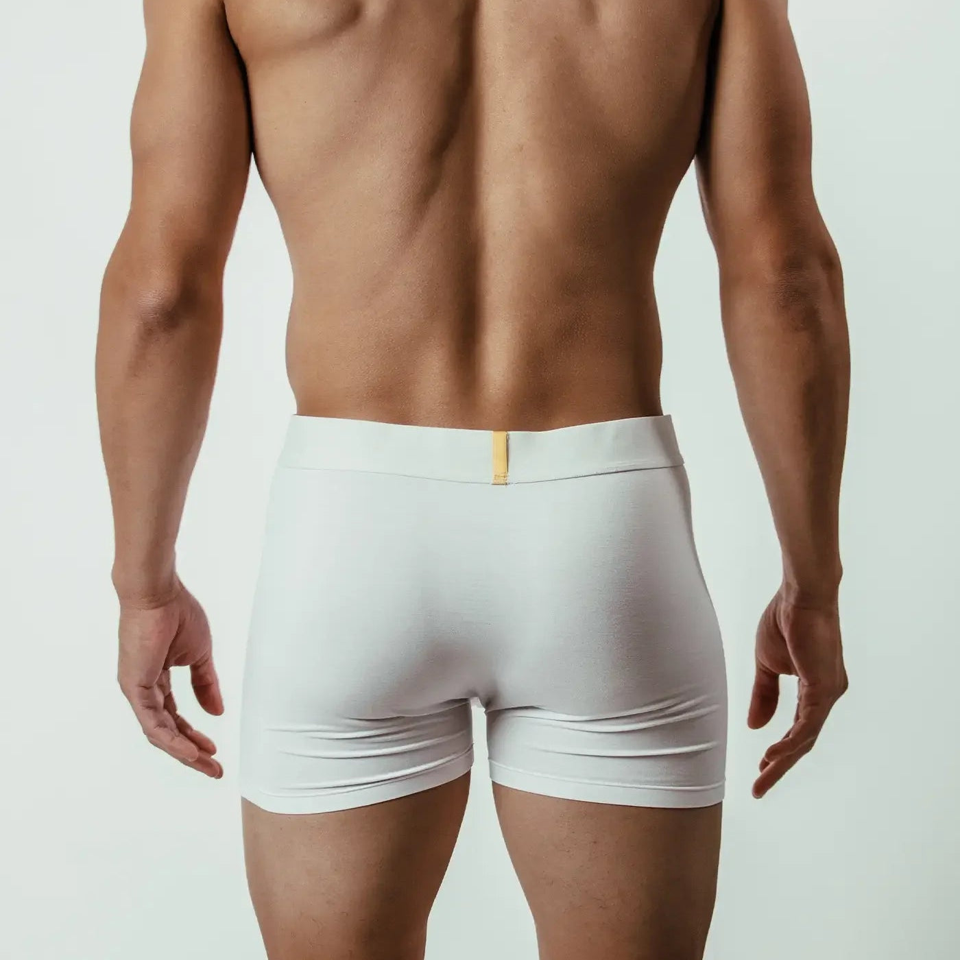 Back view of man wearing white bamboo boxer briefs, minimalist studio background
